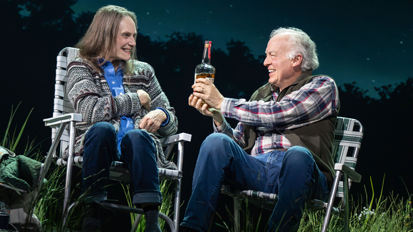 A person and person sitting in chairs holding a bottle of alcohol
Description automatically generated