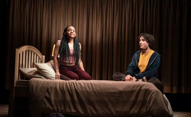 A person and person sitting on a bed
Description automatically generated