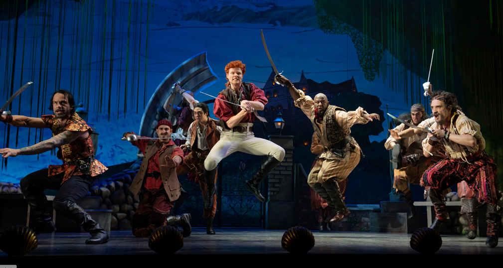 A group of men in clothing on a stage
Description automatically generated
